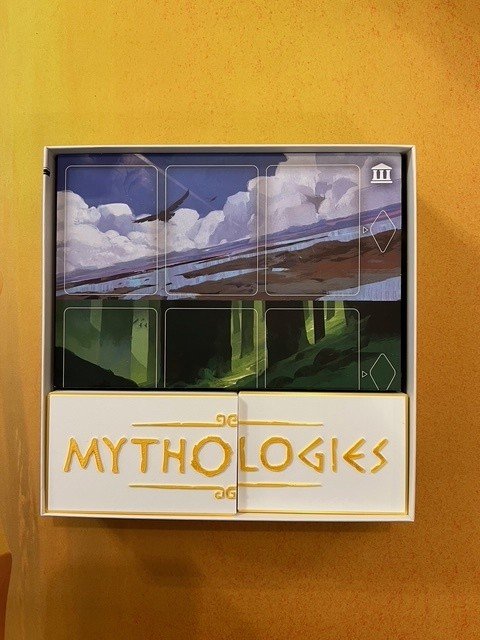 Boîte du jeu Mythologies présentée fermée sur une table en bois